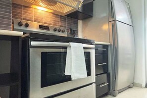 A kitchen with a stainless steel oven, a built-in microwave, and a refrigerator.