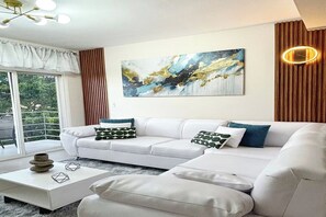 Ein modernes Wohnzimmer mit einer Eckcouch, einem Couchtisch und einem großen abstrakten Gemälde an der Wand.