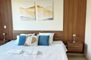 Una habitación de hotel con una cama grande, dos mesitas de noche y una obra de arte en la pared.