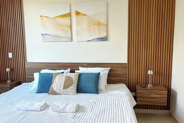 Una habitación de hotel con una cama grande, dos mesitas de noche y una obra de arte en la pared.