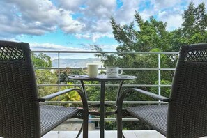 A balcony with wicker chairs, a small round table, and a mug labeled 'CAFE LATTE'.
