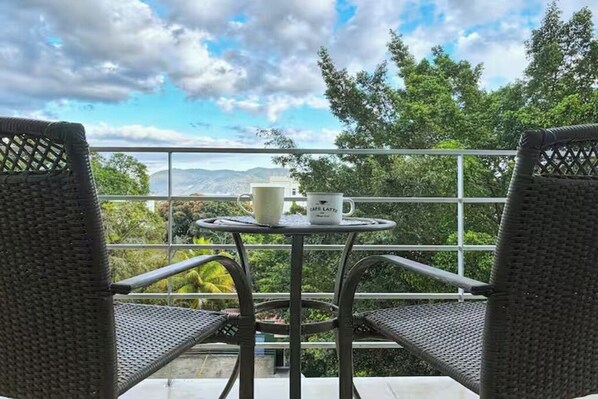A balcony with wicker chairs, a small round table, and a mug labeled 'CAFE LATTE'.