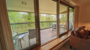 A room with a sliding glass door leading to an outdoor deck with a table and chairs. - Saints John 2515 (Keystone)