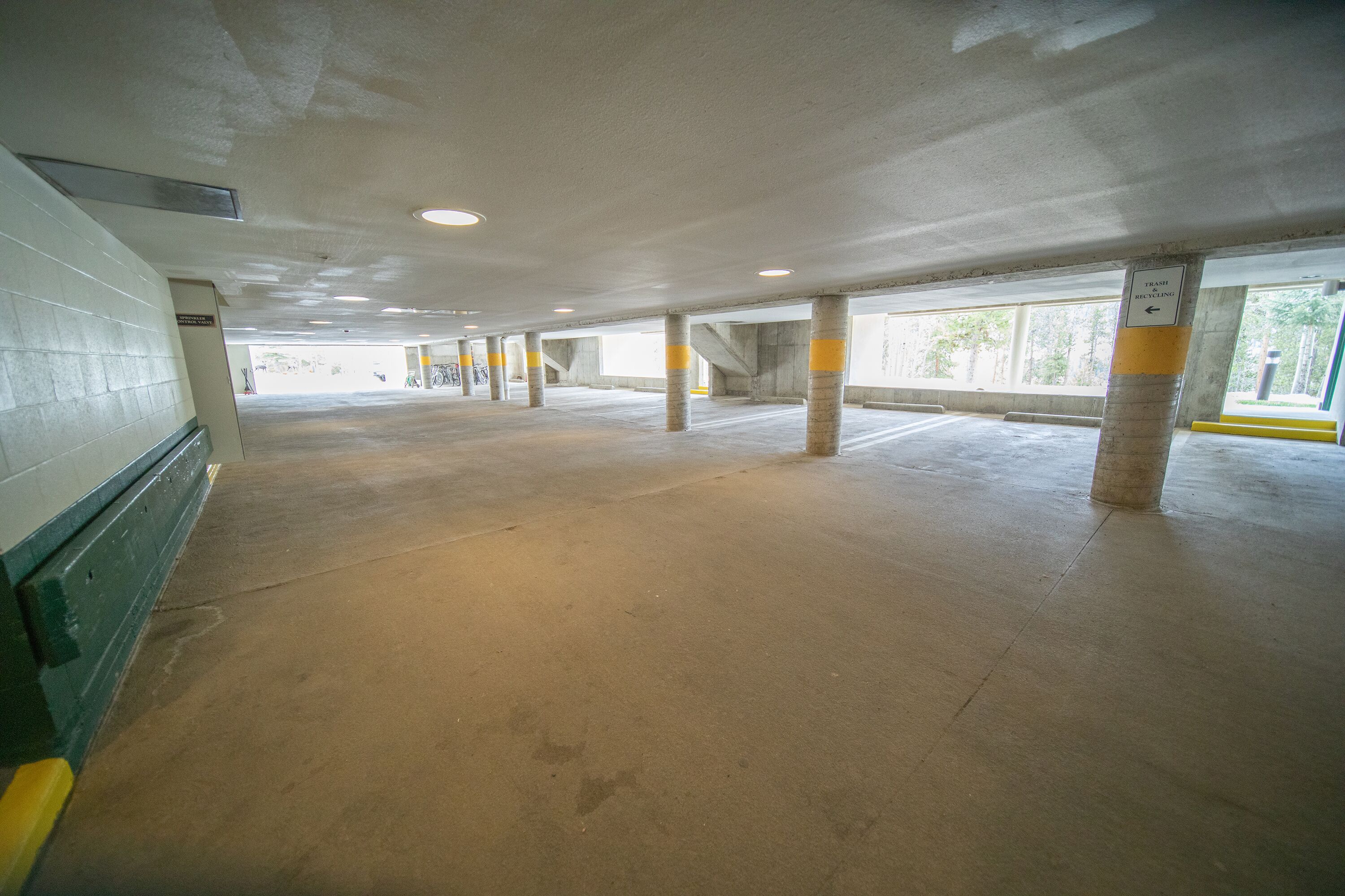 Ett tomt parkeringsgarage med betongpelare, ett betonggolv och en vägg med en skylt.