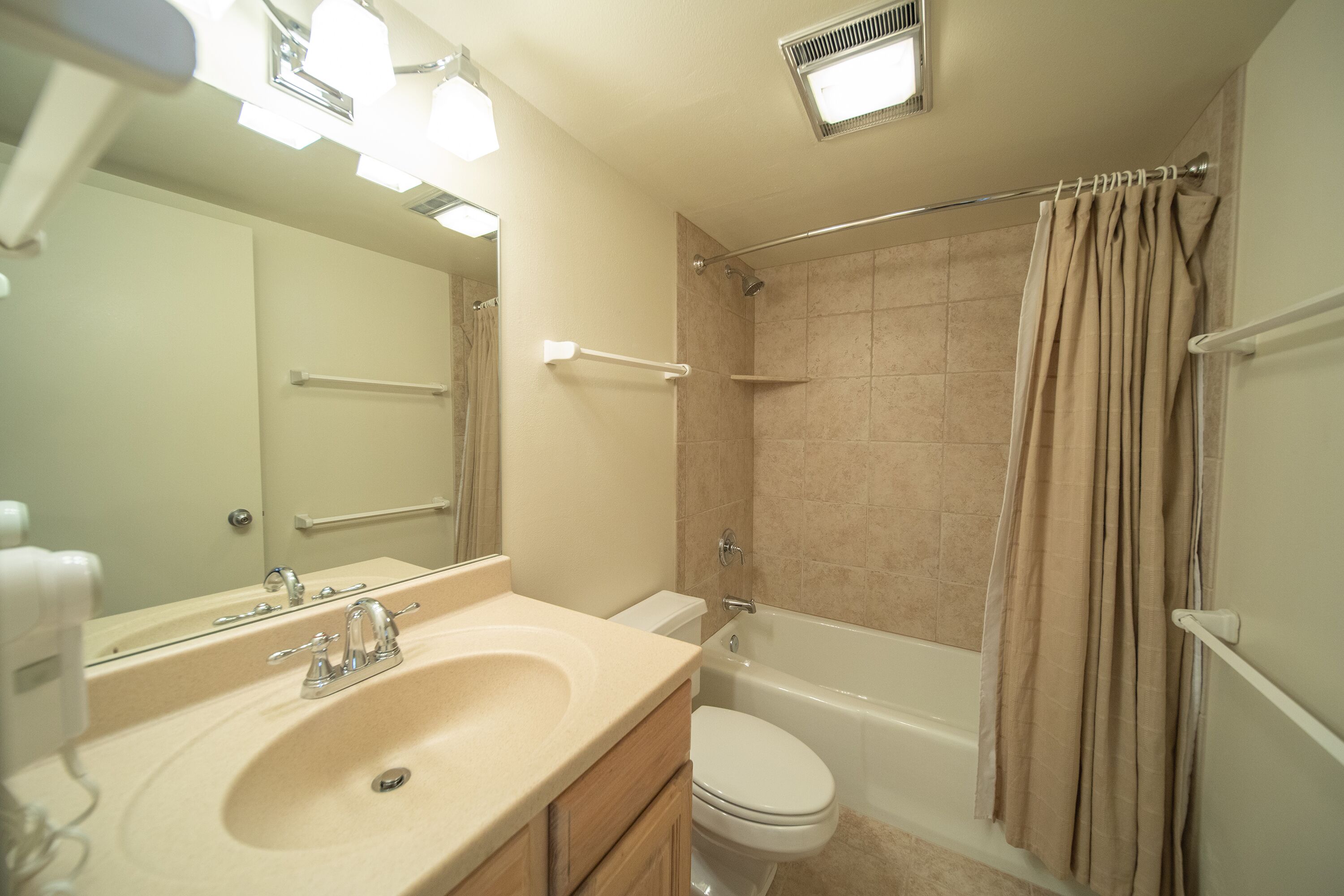 A bathroom with a sink, mirror, toilet, and bathtub.