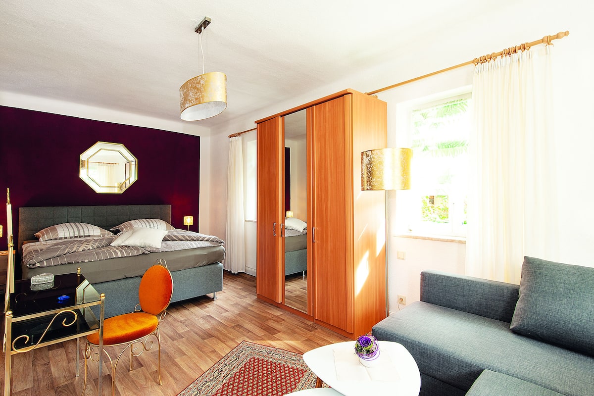 Een moderne slaapkamer met een bed, een bank, een stoel en een bureau.