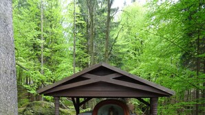 A rustic wooden structure with a mural, surrounded by a forest.