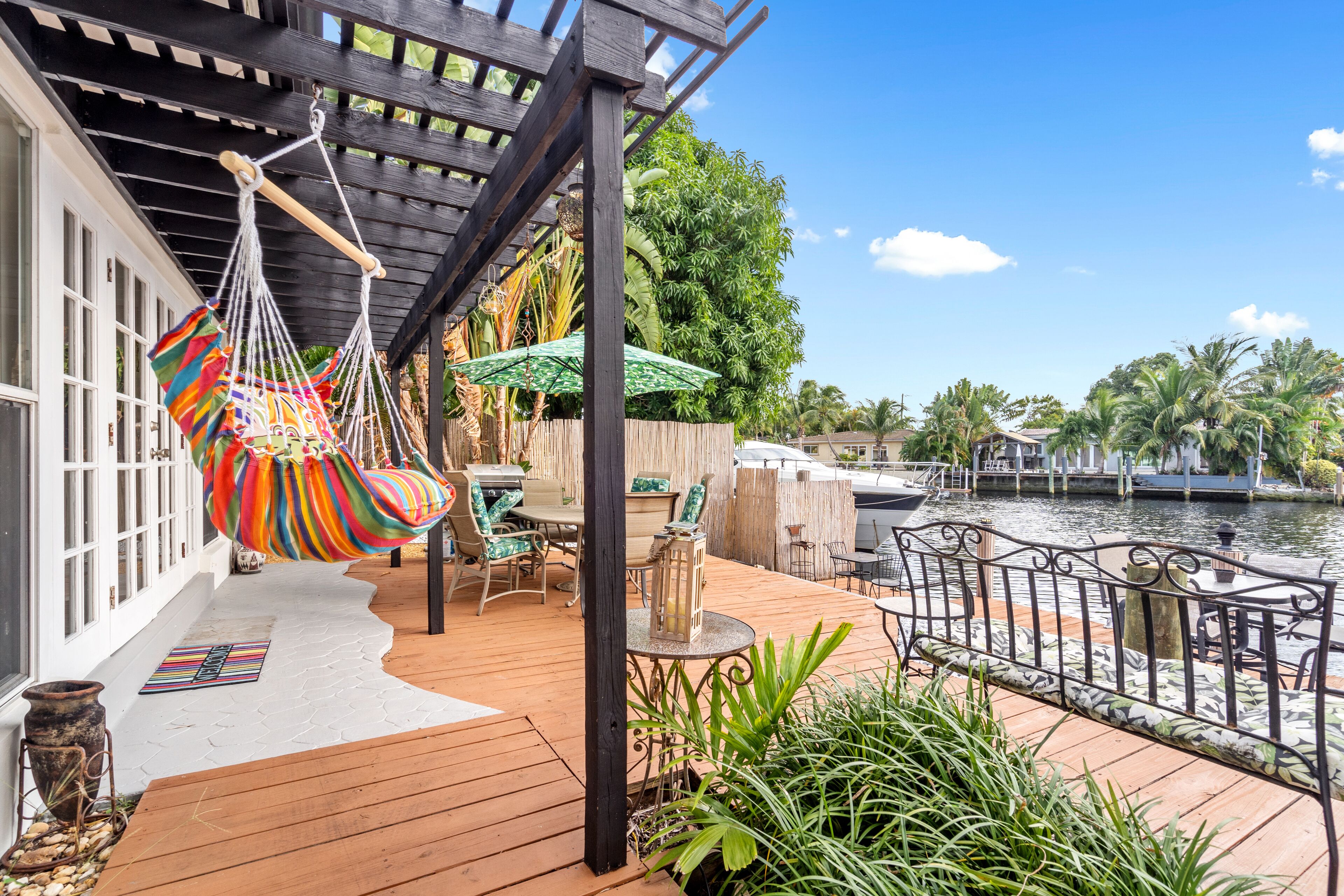 A wooden deck with outdoor furniture, a hammock, and a view of a river.