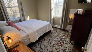 Une chambre à coucher avec un lit, une table de chevet, une lampe et un téléviseur fixé au mur.