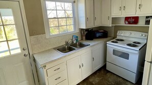 Une cuisine avec des meubles blancs, une cuisinière et un évier.