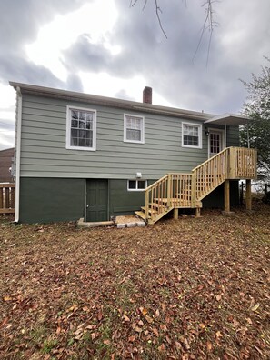 A two-story house with a wooden staircase leading to a deck, surrounded by a yard covered in fallen leaves. - 🥤The Coca Cola House 🥤 (Roanoke)