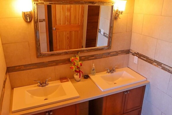 Un baño con dos lavamanos, un espejo y un florero con flores.