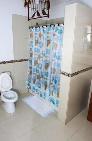 Bathroom features a shower, toilet, and nautical-themed shower curtain.
