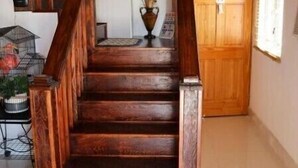 Una escalera de madera con barandilla que lleva a un rellano con una puerta y una ventana de madera.