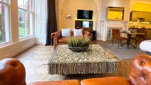 Un salón amplio con un sofá de cuero, una mesa de centro de cristal con una planta y una chimenea.
