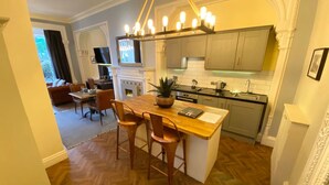 Una cocina moderna con una isla de madera, taburetes de bar y una araña.