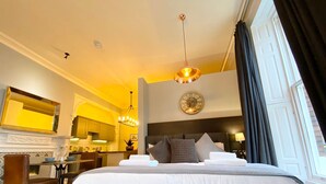 Habitación de hotel con una cama grande, un área de comedor y vistas al exterior.
