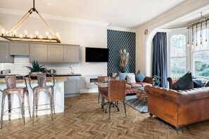 Una cocina moderna con una isla central, armarios grises y un televisor de pantalla plana.