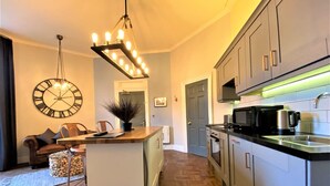 Uma cozinha moderna com ilha central, eletrodomésticos embutidos e um relógio grande na parede.