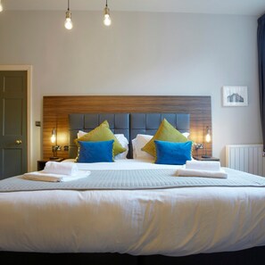 A hotel room with a large bed, a wooden headboard, and two bedside lamps. - Claremont The Matcham (Leeds)