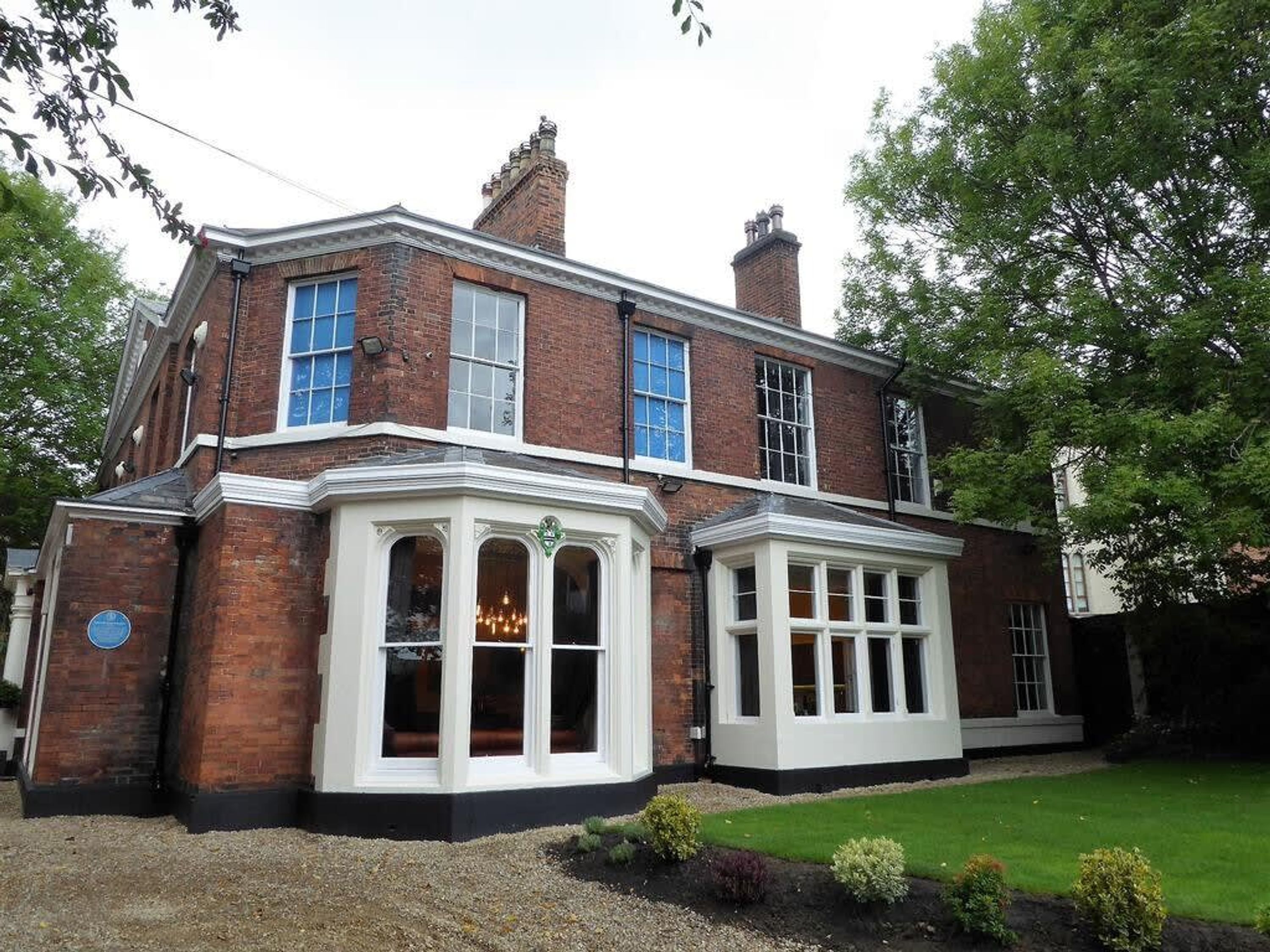 A two-story brick house with a bay window and a front porch.