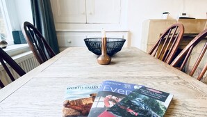 A dining table with magazines and a candle holder.