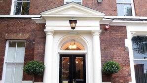 A building with a black door, white columns, and two potted plants. - Claremont The Smeaton (Leeds)