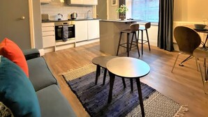 A modern kitchen with white cabinets, a central island, and pendant lighting. - Claremont The Smeaton (Leeds)