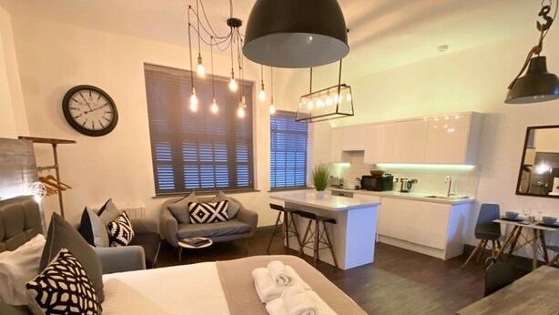 A modern hotel room with a large bed, a desk, and a kitchenette. - Coach House Studio in Leeds (Leeds)