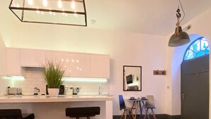 A modern kitchen with a central island, bar stools, and a dining area with a table and chairs. - Coach House Studio in Leeds (Leeds)