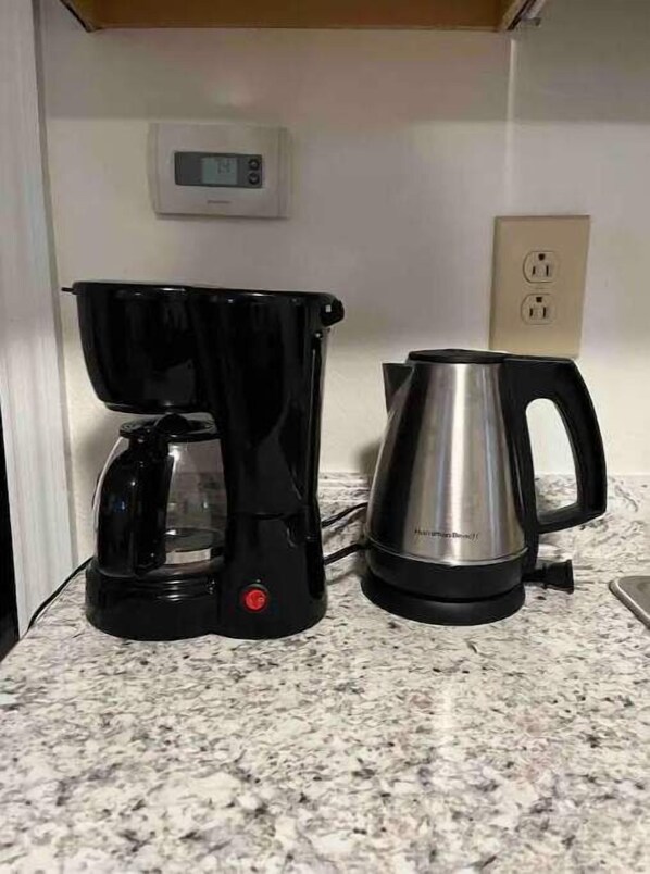Une cuisine équipée d’une machine à café et d’une bouilloire, le tout posé sur un plan de travail en granit.