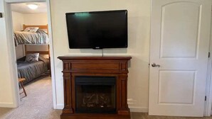 A room with a fireplace, a television mounted above it, and a door to the right.