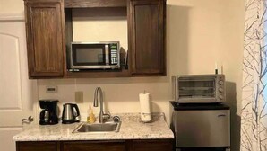 A kitchen with wooden cabinets, a microwave, a toaster oven, a sink, and a coffee maker.