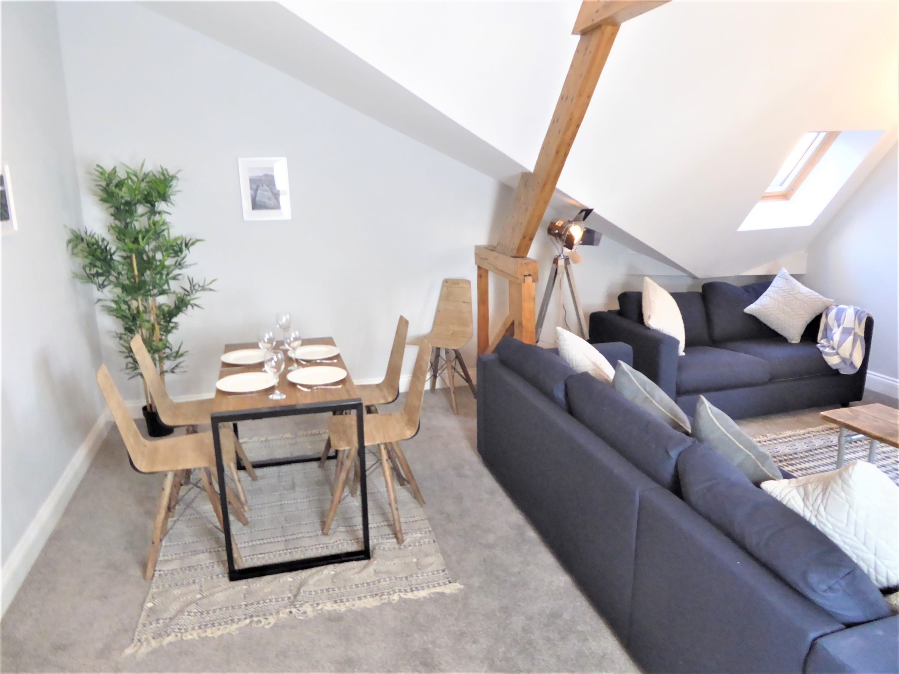 Un espacio habitable tipo loft con comedor, sofá y un ventanal grande.