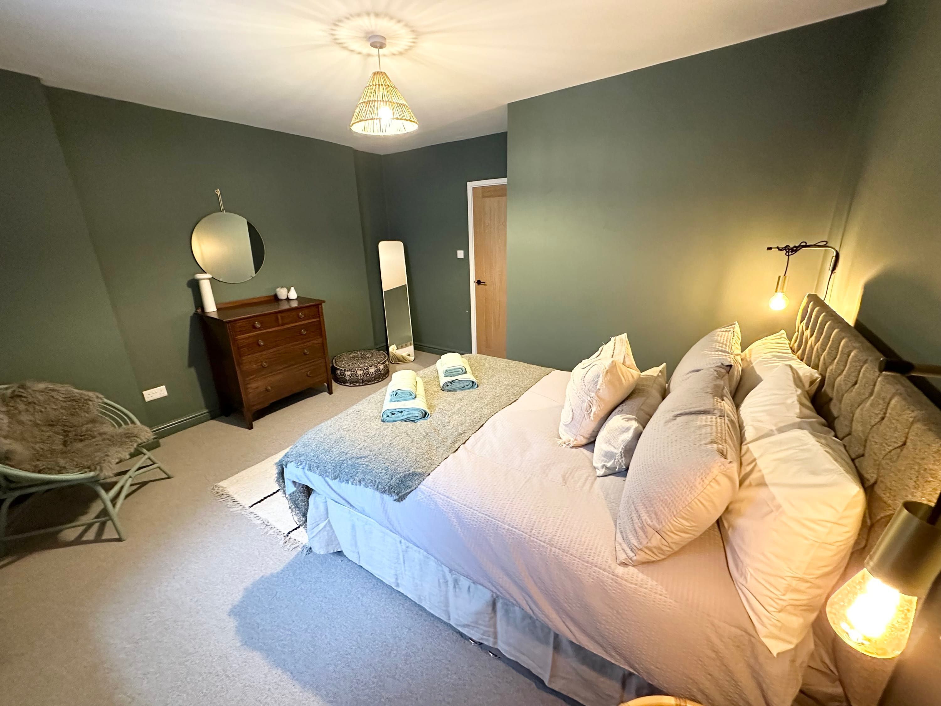 Ein Schlafzimmer mit einem Bett, einem Schminktisch, einem Stuhl und einem Spiegel.