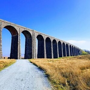 A long viaduct with multiple arches over a gravel path.