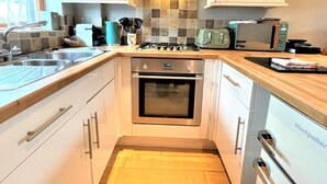 A compact kitchen with white cabinets, a stainless steel sink, a gas stove, and a microwave.