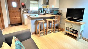 A compact living space with a kitchenette, a dining area, and a seating area with a sofa and chairs.