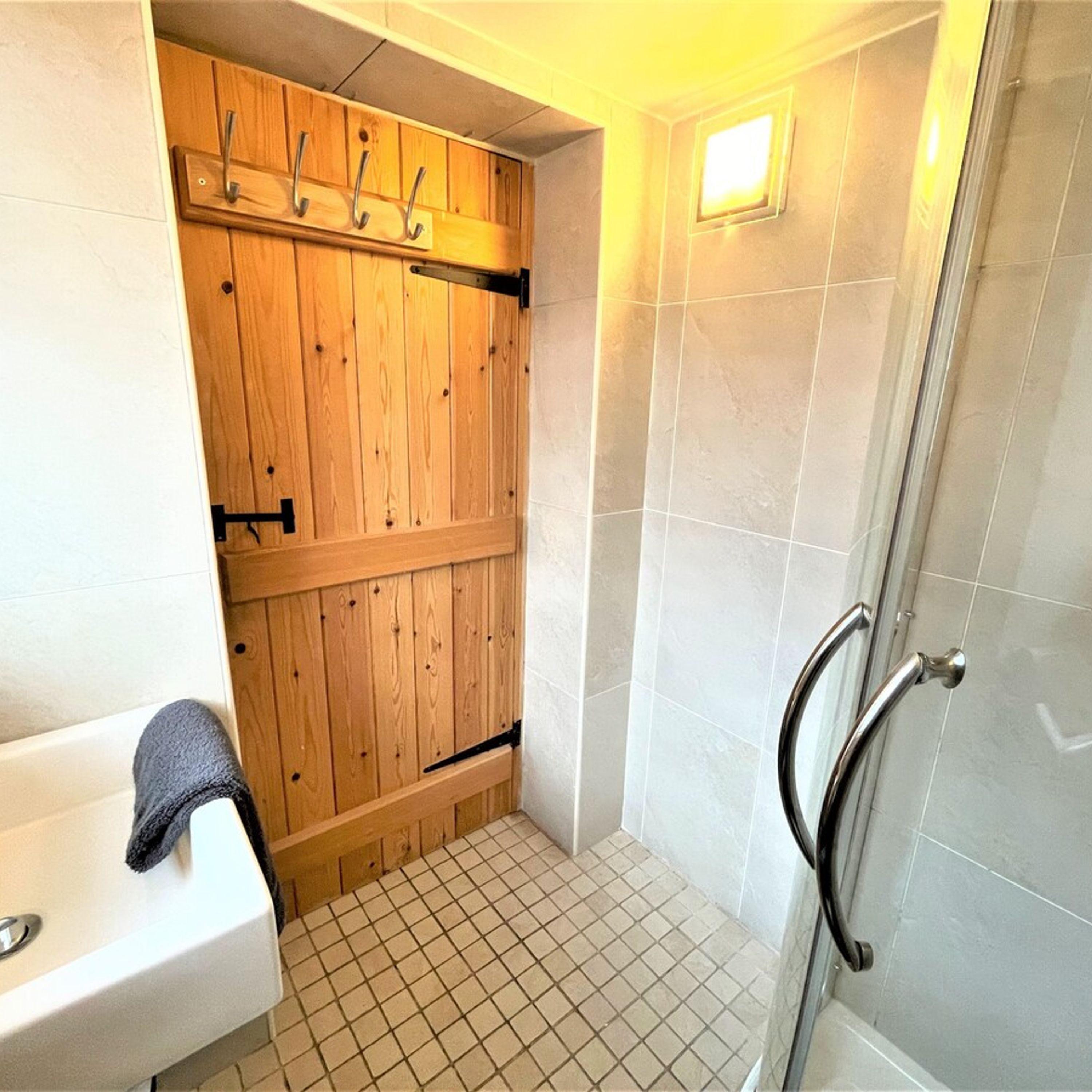 A bathroom with a wooden cabinet, a sink, and a shower area.