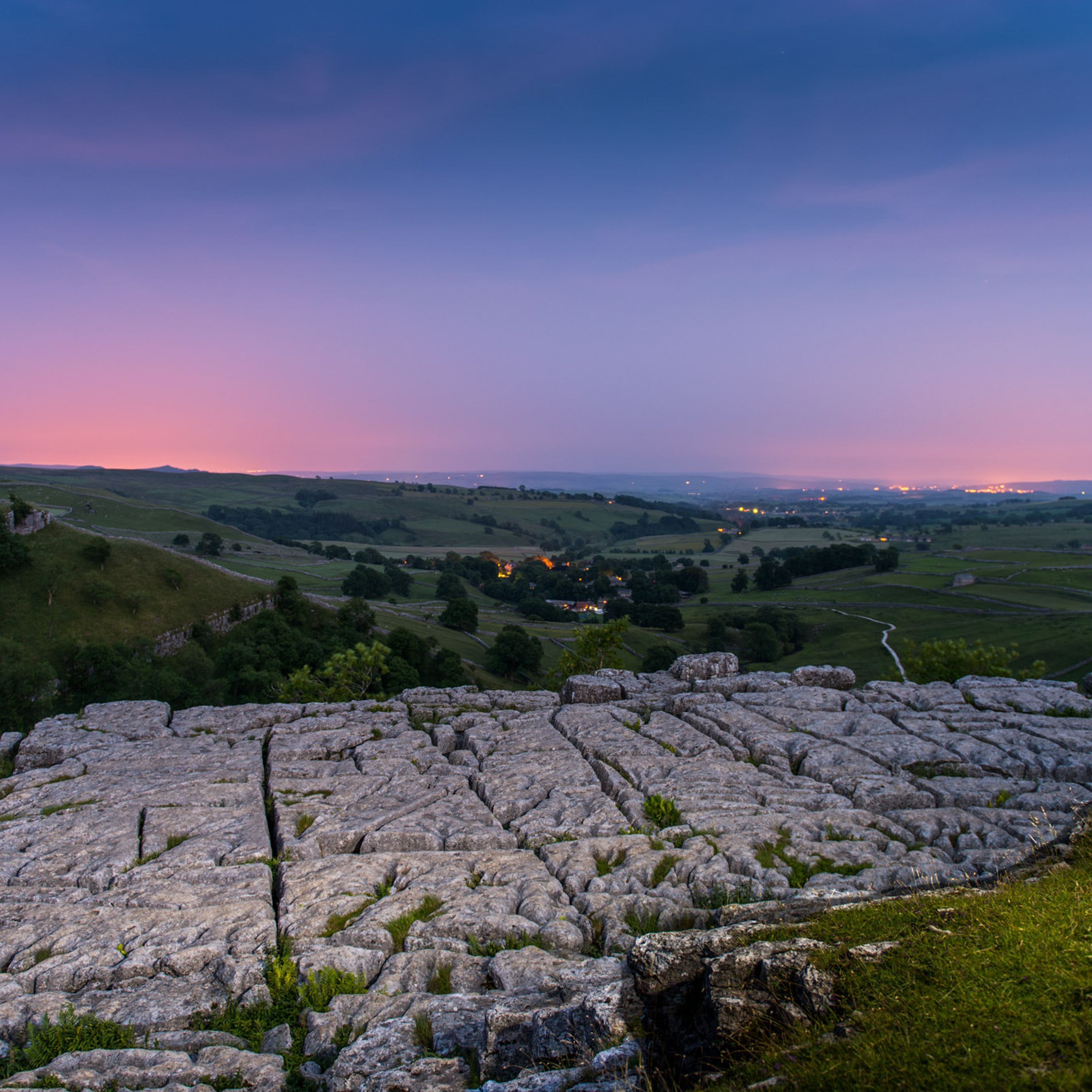 A stone ruin with a panoramic view of a valley and distant lights.