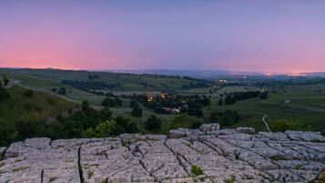 A stone ruin with a panoramic view of a valley and distant lights.
