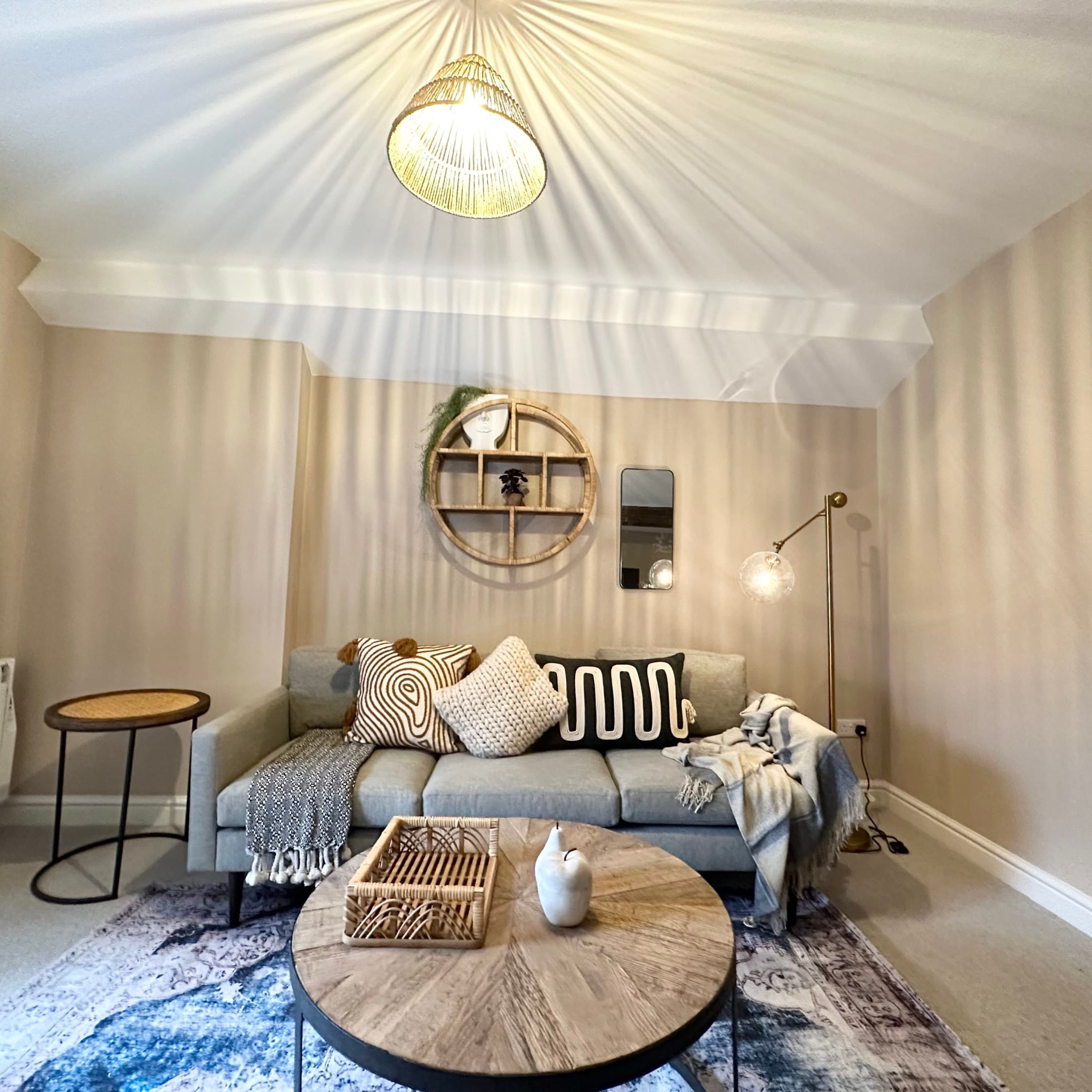A cozy living room with a grey sofa, round coffee table, and a hanging light fixture.