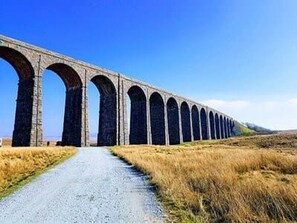 A long stone viaduct with multiple arches over a gravel path.