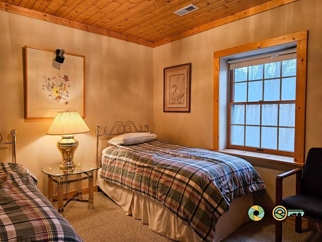 A bedroom with two beds, a window, and a lamp.