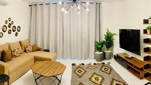 A modern living room with a sofa, coffee table, TV, and decorative items. - Ground Spacious 1-BR Apt @ SwanLake - El Gouna (Red Sea Governorate)