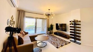 A modern living room with a sofa, a coffee table, a TV, and a patterned rug. - Ground Spacious 1-BR Apt @ SwanLake - El Gouna (Red Sea Governorate)