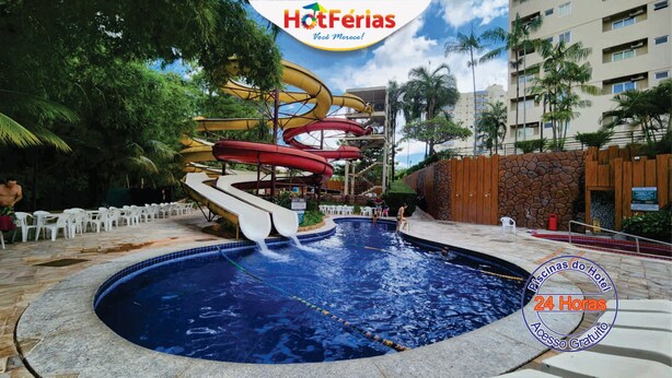 Una piscina con varias toboganes de agua, rodeada de palmeras y un muro de piedra.