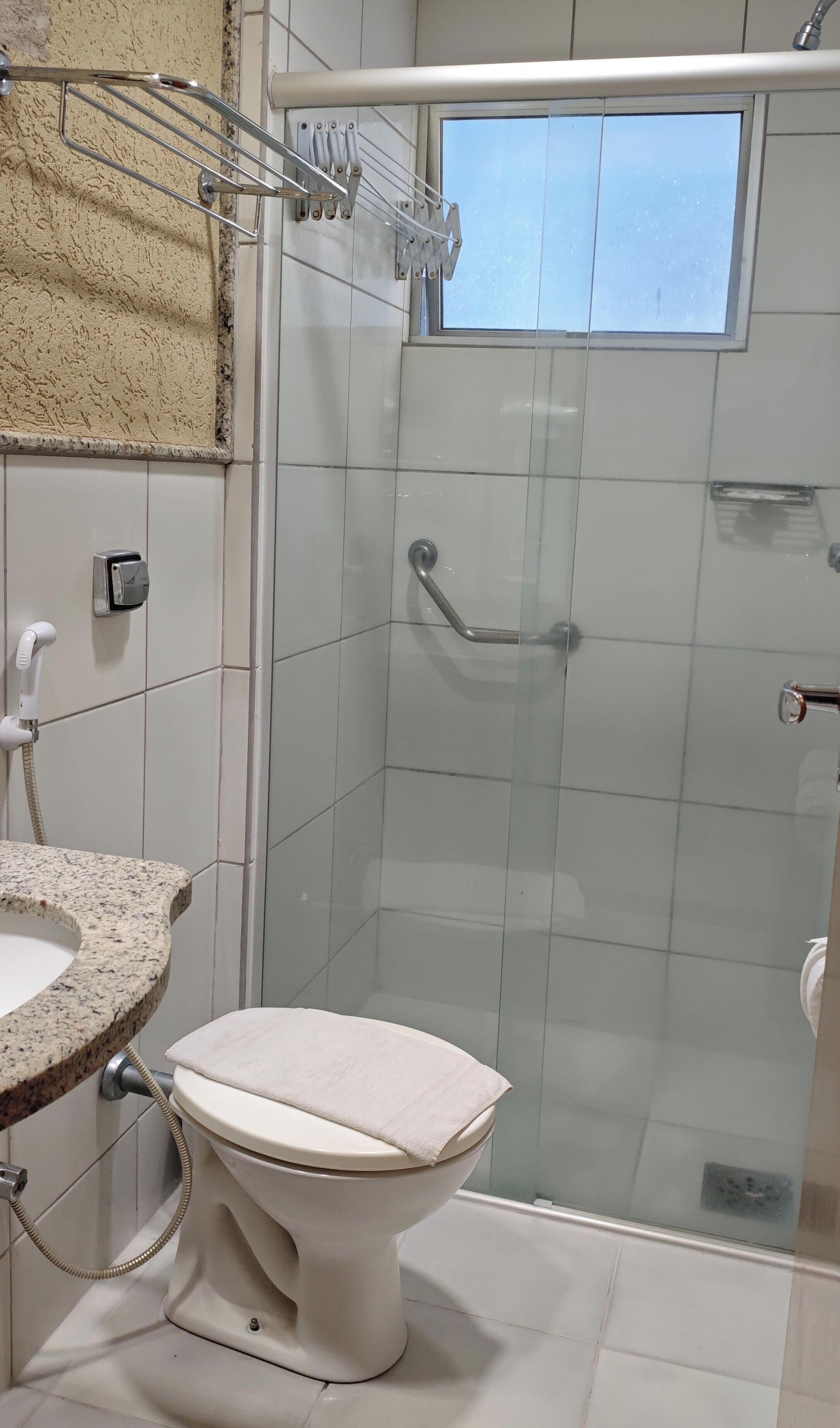 Un baño con inodoro, lavabo, ducha y ventana.