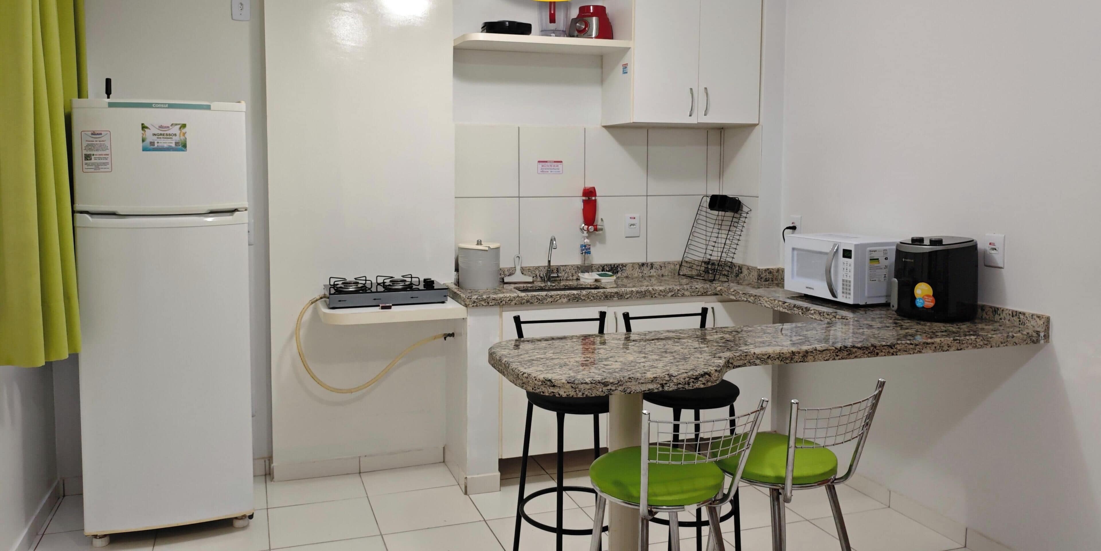 Une cuisine compacte équipée d’un réfrigérateur, d’une cuisinière, d’un four à micro-ondes et de tabourets de bar.