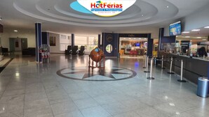 Un vestíbulo amplio con una escultura central de un globo terráqueo, una cafetería y un mostrador de recepción.